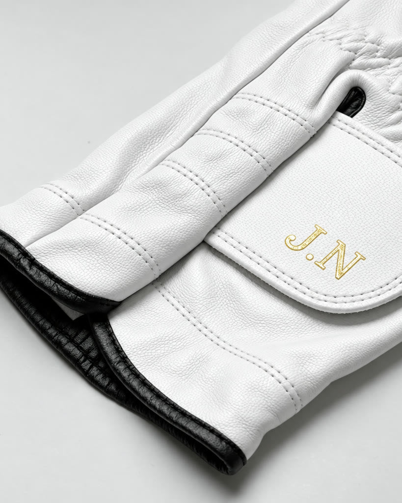 Close-up of the wrist strap: initials J.N hot-stamped in gold foil, black leather trim at the cuff.