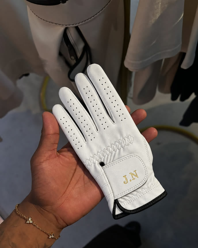 The Monogram Glove held in an open hand, initials J.N on the strap.